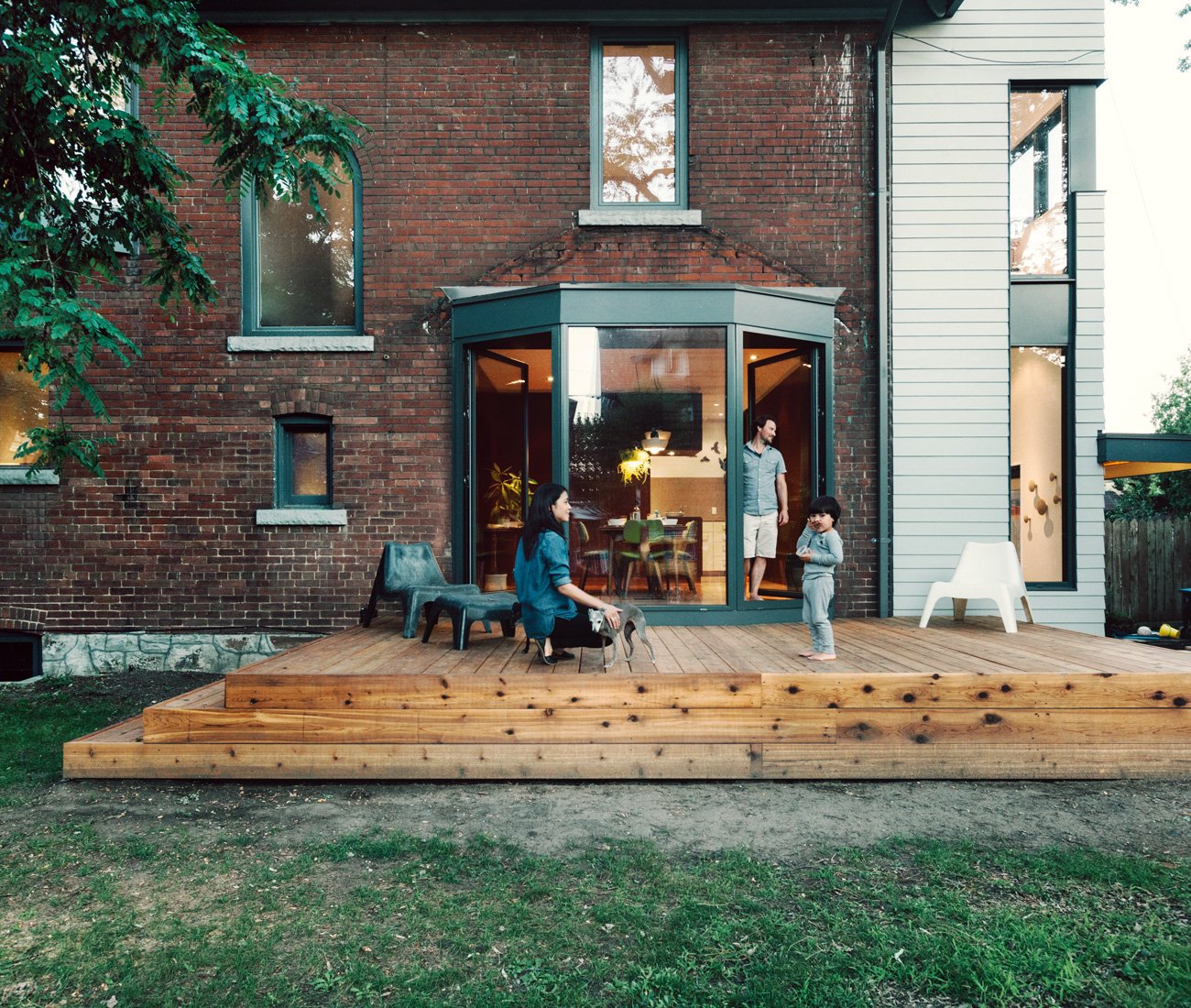 Toronto Edwardian home with a modern floor-to-ceiling glass door, connecting the dining room to a spacious wood deck and backyard patio.