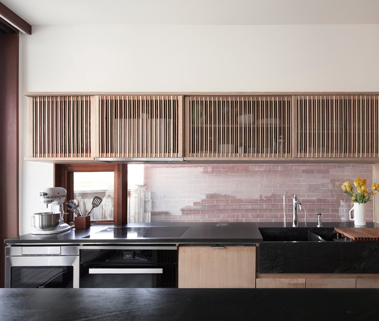 Sliding slatted oak doors in the kitchen conceal tableware and appliances.