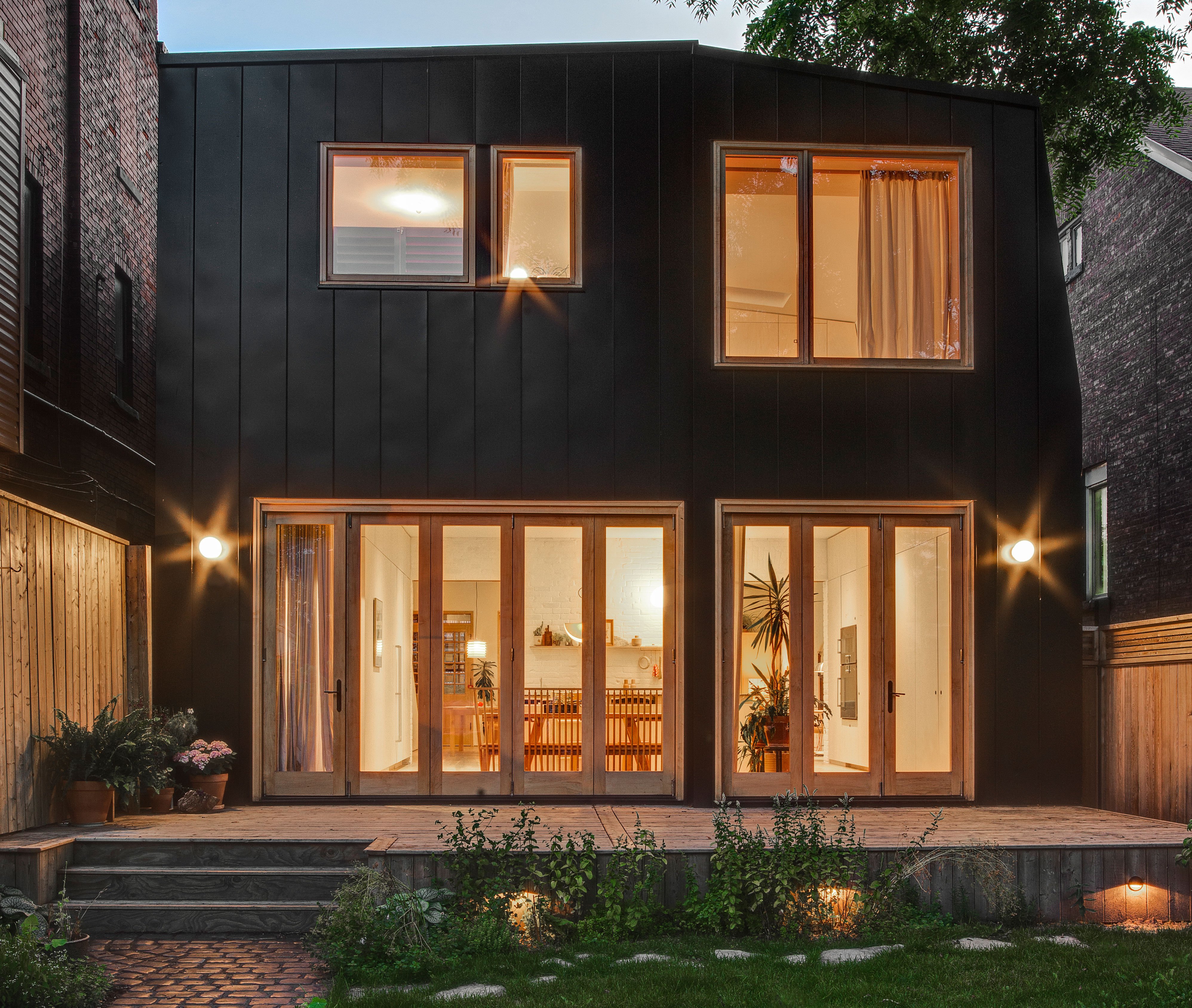 Elevated backyard patio, featuring an aluminum-clad addition, built-in lighting, and a cobblestone pathway.