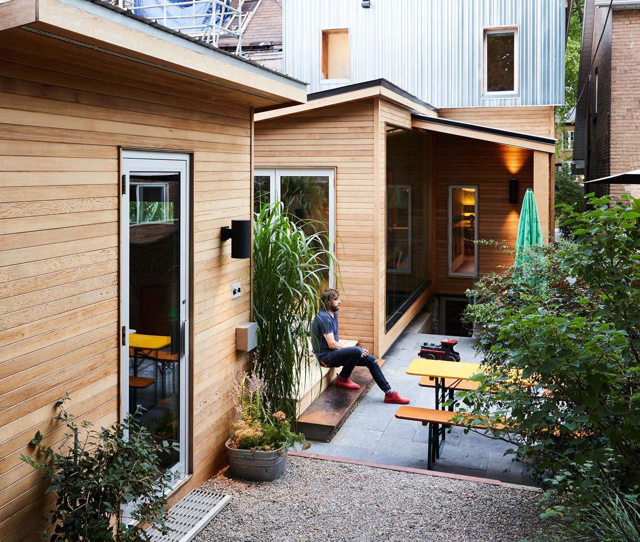 Backyard with tiered patio, elevated deck, cedar facades, and lush greenery creating a secluded retreat.