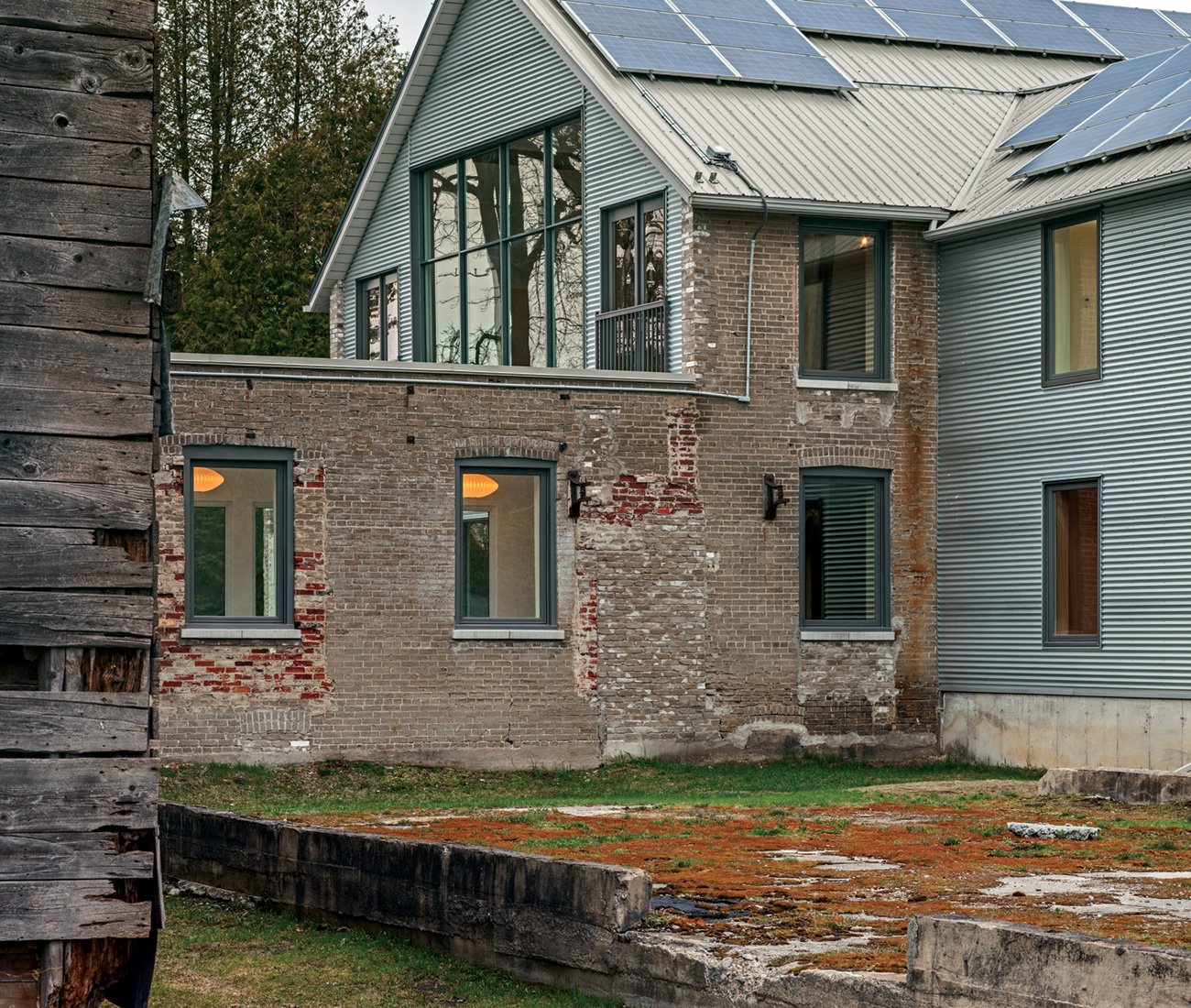 Renovated industrial factory with original red brick, steel cladding, and modern interior blending contemporary style with heritage.
