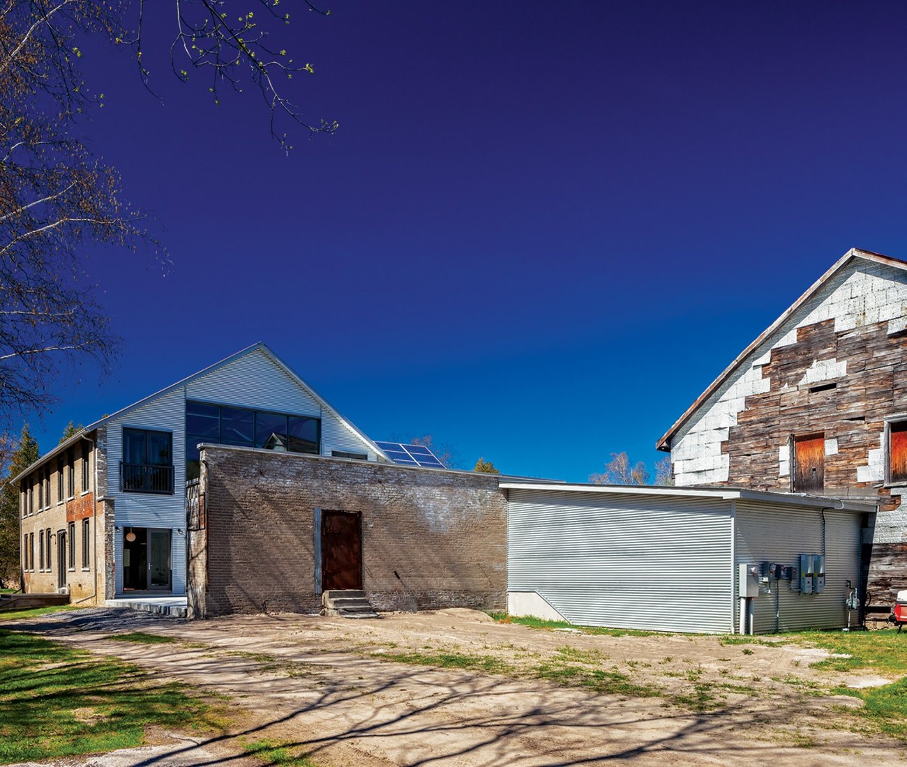 Exterior view of the renovated century-old industrial brick factory, featuring original red brick and modern steel cladding, blending industrial heritage with contemporary design elements.